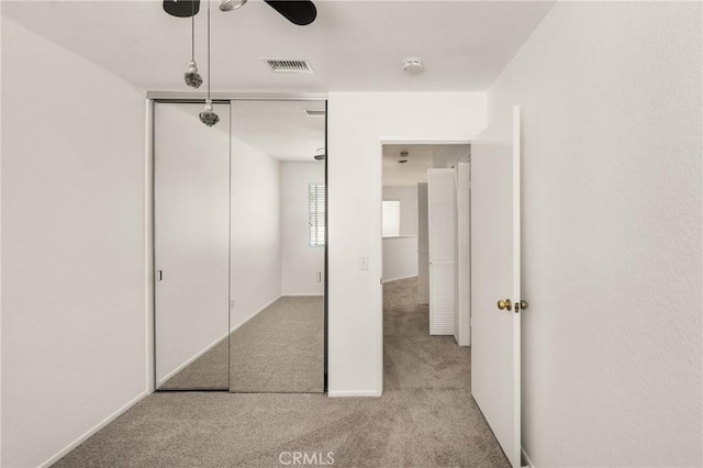 unfurnished bedroom featuring light colored carpet, a closet, and visible vents