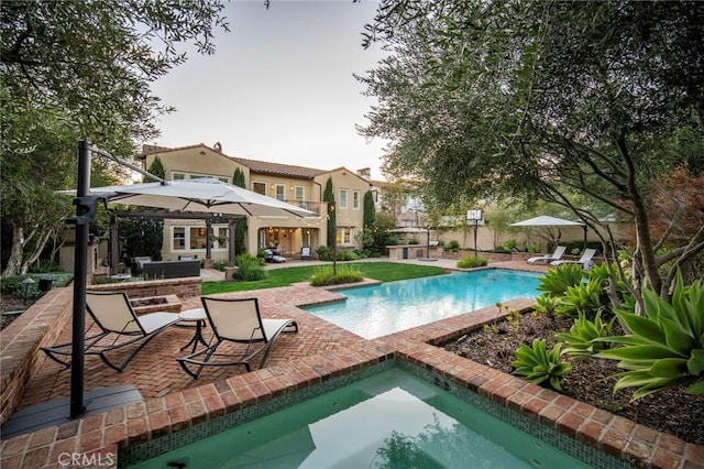 outdoor pool with a patio and a hot tub