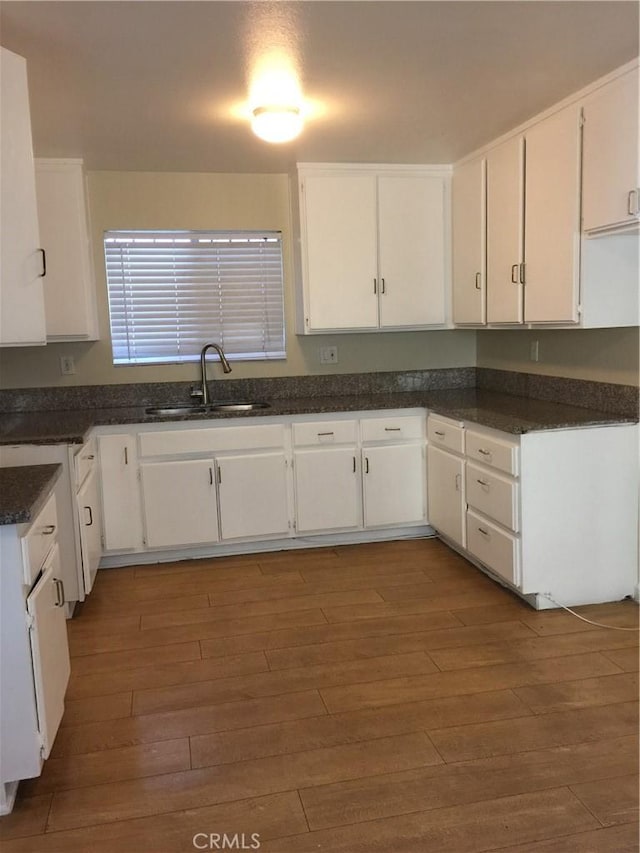 kitchen featuring dark wood finished floors, white cabinets, and a sink