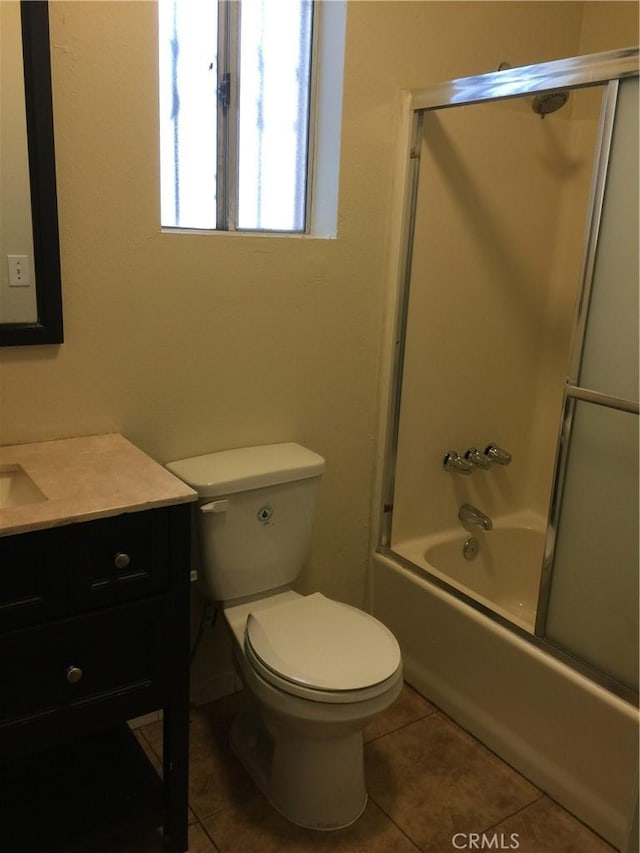 full bath featuring enclosed tub / shower combo, toilet, vanity, and tile patterned floors