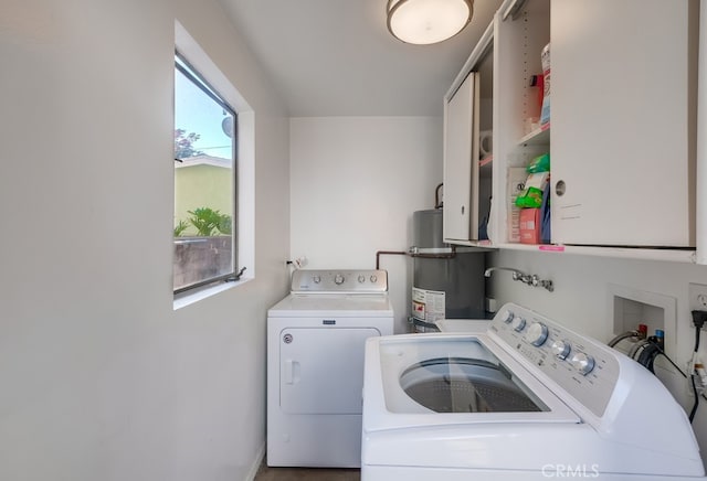 clothes washing area with cabinet space, independent washer and dryer, and secured water heater