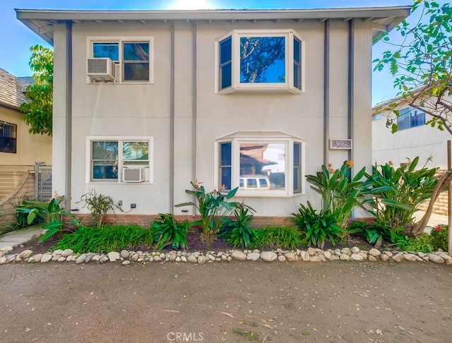 view of front of house featuring stucco siding and cooling unit