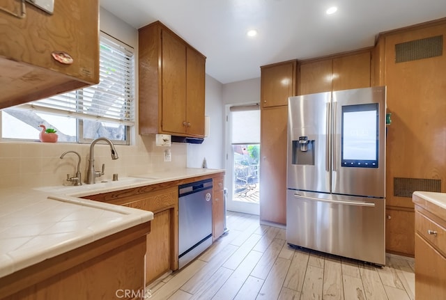 kitchen featuring appliances with stainless steel finishes, brown cabinets, a sink, and decorative backsplash