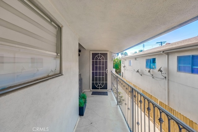 view of exterior entry featuring a balcony and stucco siding