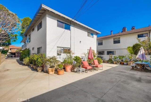 rear view of house featuring stucco siding, cooling unit, a patio, and fence