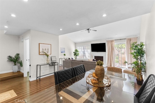 dining space featuring recessed lighting, a fireplace, wood finished floors, a ceiling fan, and baseboards