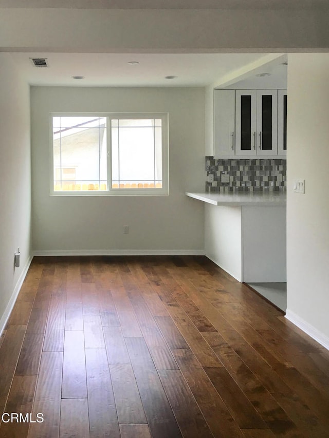 interior space featuring decorative backsplash, dark wood finished floors, visible vents, and white cabinets