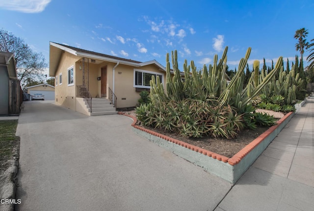 view of front facade featuring crawl space, a detached garage, and stucco siding