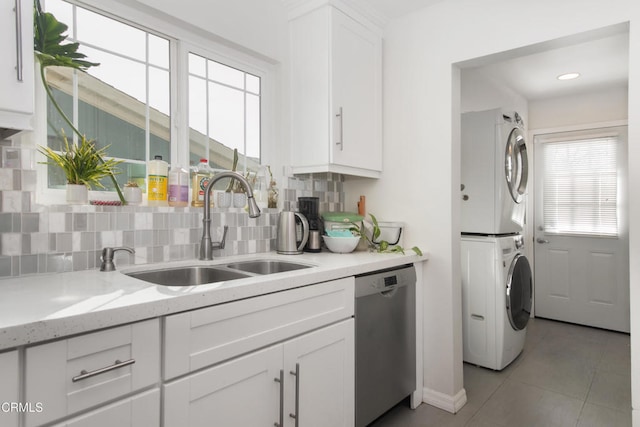 washroom with a sink, stacked washing maching and dryer, and light tile patterned floors