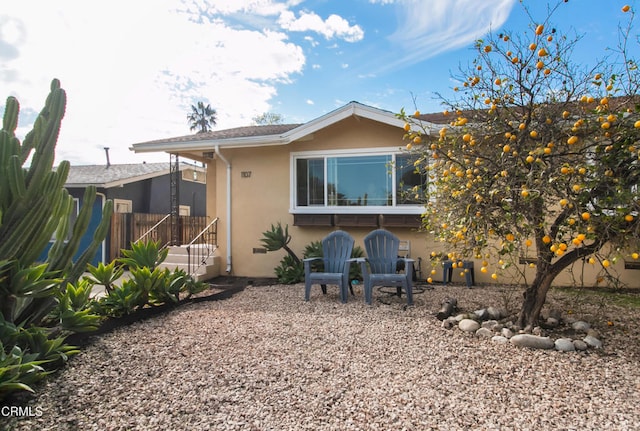 rear view of house with fence and stucco siding