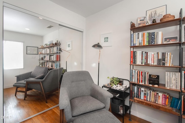 living area with visible vents, baseboards, and wood finished floors