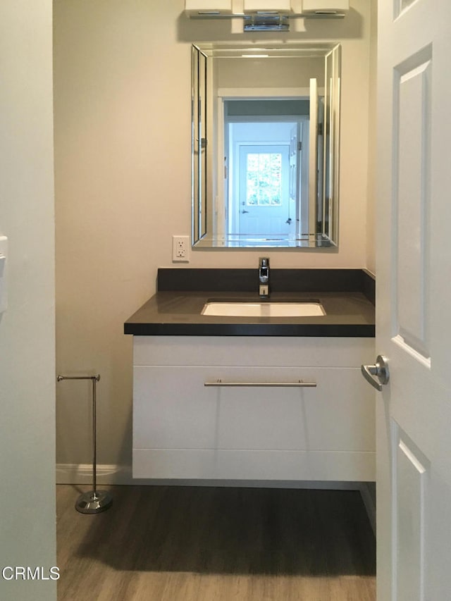 bathroom with baseboards, wood finished floors, and vanity