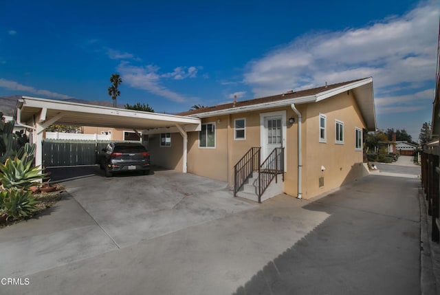 view of front of home featuring driveway, fence, an attached carport, and stucco siding