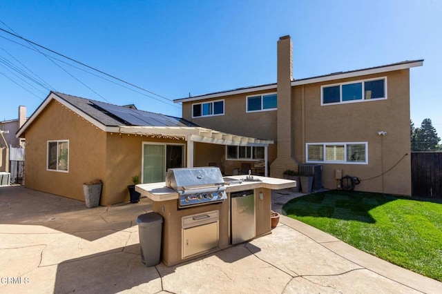 rear view of house featuring exterior kitchen, a patio area, a yard, and stucco siding