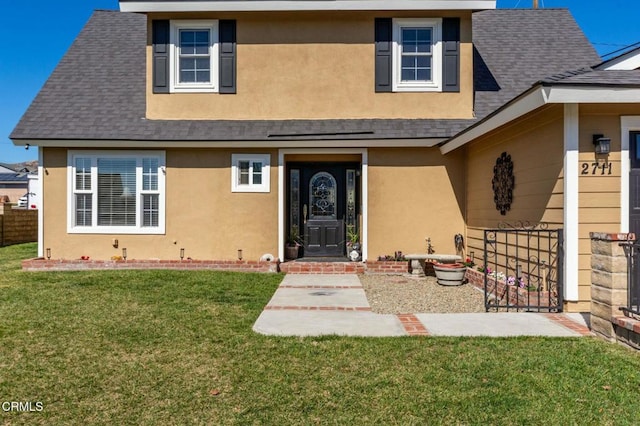 view of front of home with roof with shingles, a front lawn, and stucco siding