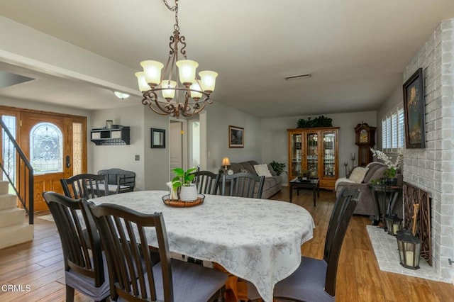 dining room featuring light wood-style floors, visible vents, a fireplace, and stairway