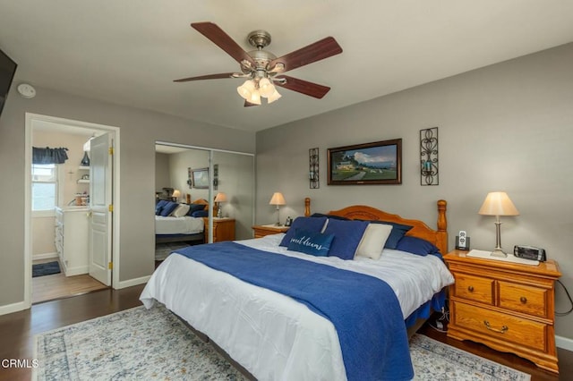 bedroom with baseboards, a ceiling fan, ensuite bath, dark wood-type flooring, and a closet