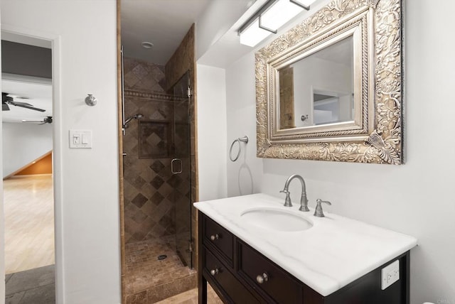 full bathroom featuring ceiling fan, a shower stall, and vanity