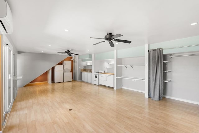 unfurnished living room featuring ceiling fan, an AC wall unit, recessed lighting, and light wood-style floors