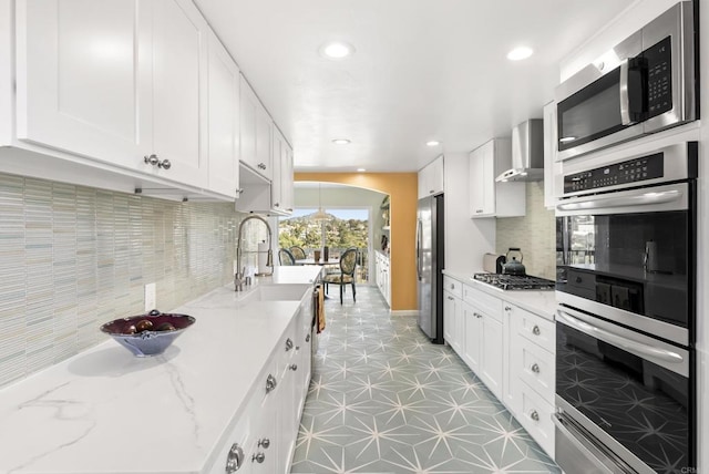 kitchen featuring appliances with stainless steel finishes, white cabinets, decorative backsplash, and light stone countertops