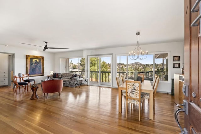 dining space with ceiling fan with notable chandelier, wood finished floors, and a wealth of natural light