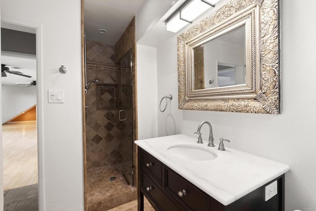 full bath featuring a ceiling fan, vanity, and a shower stall