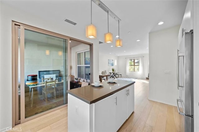 kitchen featuring white cabinetry, light wood-type flooring, visible vents, and stainless steel refrigerator