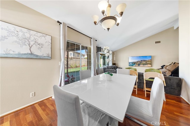 dining area featuring a notable chandelier, wood finished floors, visible vents, baseboards, and vaulted ceiling