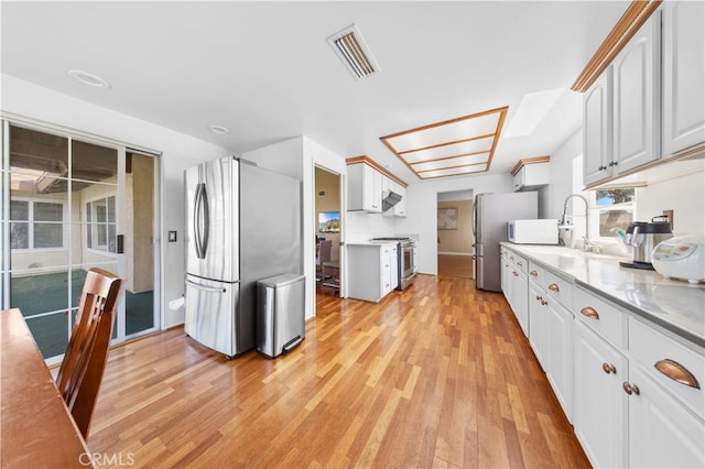 kitchen with stainless steel appliances, visible vents, white cabinetry, light countertops, and light wood finished floors