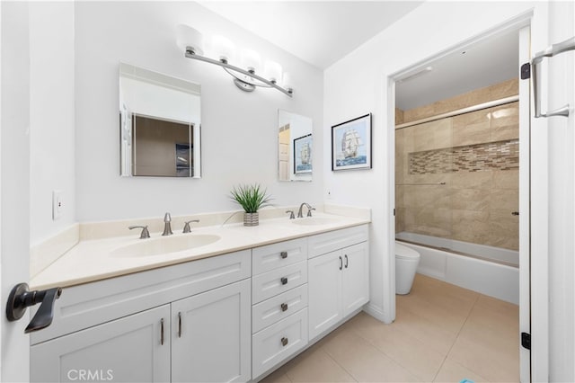 full bath featuring toilet, double vanity, a sink, and tile patterned floors