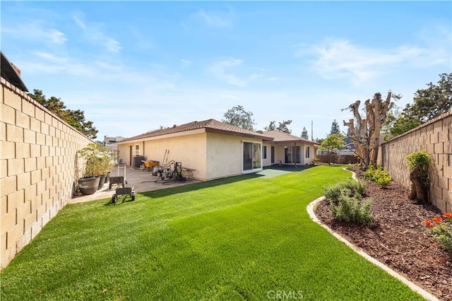 rear view of property with a patio, central AC unit, a fenced backyard, a yard, and stucco siding