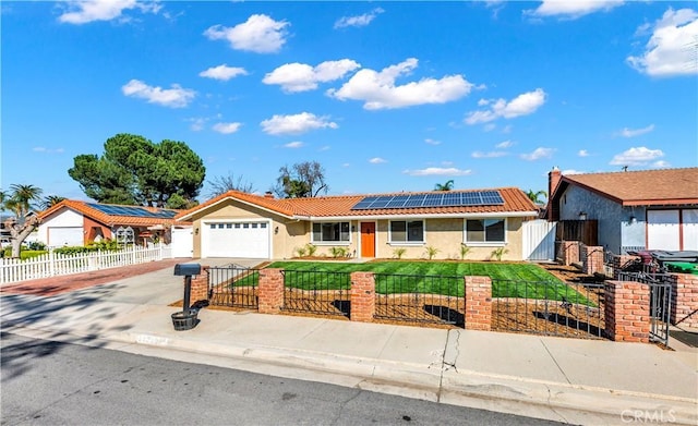 single story home featuring a fenced front yard, roof mounted solar panels, a tile roof, and concrete driveway