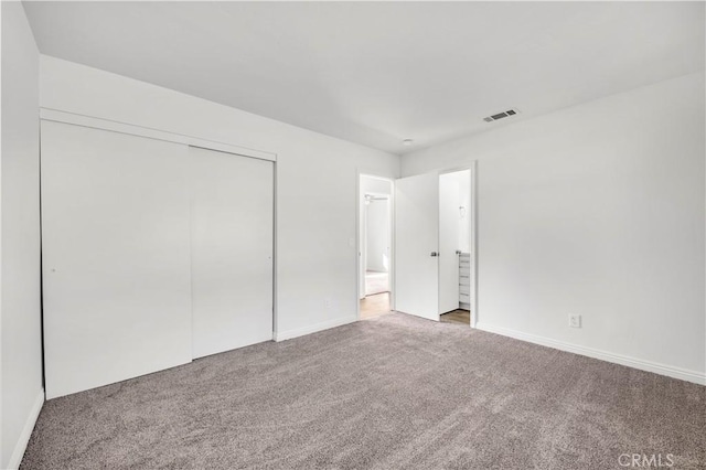 unfurnished bedroom featuring a closet, carpet flooring, visible vents, and baseboards