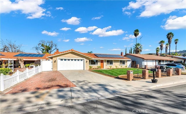 single story home with a garage, concrete driveway, a fenced front yard, a tiled roof, and roof mounted solar panels