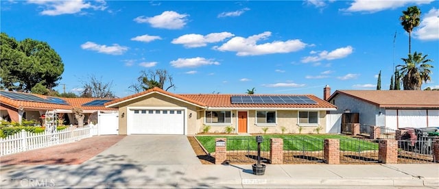 ranch-style home featuring solar panels, concrete driveway, an attached garage, fence private yard, and a tiled roof