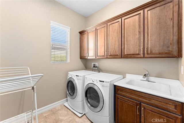 laundry room with washing machine and clothes dryer, a sink, cabinet space, and baseboards