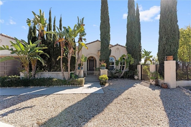 mediterranean / spanish-style house with a fenced front yard, a gate, and stucco siding