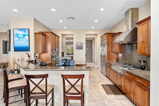 kitchen with stone counters, brown cabinets, stainless steel appliances, visible vents, and a peninsula