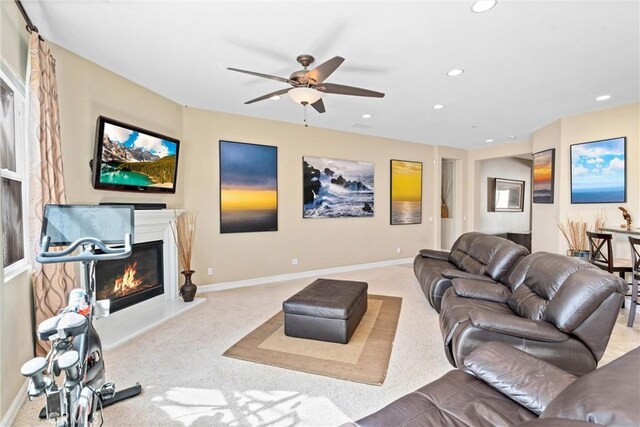 living area with recessed lighting, baseboards, light colored carpet, and a glass covered fireplace