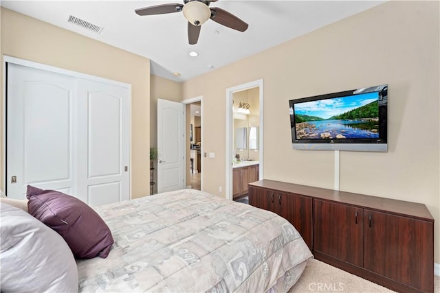 bedroom featuring visible vents, a ceiling fan, light colored carpet, ensuite bathroom, and a closet