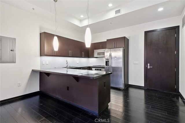 kitchen featuring visible vents, stainless steel fridge with ice dispenser, baseboards, white microwave, and a peninsula