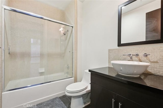 bathroom with shower / bath combination with glass door, backsplash, toilet, vanity, and tile patterned flooring