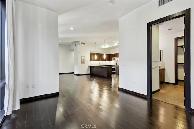 unfurnished living room with recessed lighting, baseboards, visible vents, and dark wood finished floors
