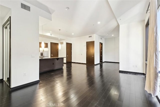 unfurnished living room with baseboards, dark wood finished floors, and visible vents