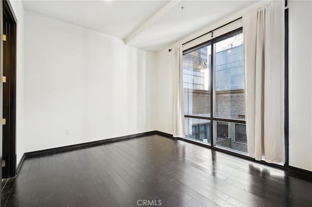 spare room featuring baseboards and wood finished floors