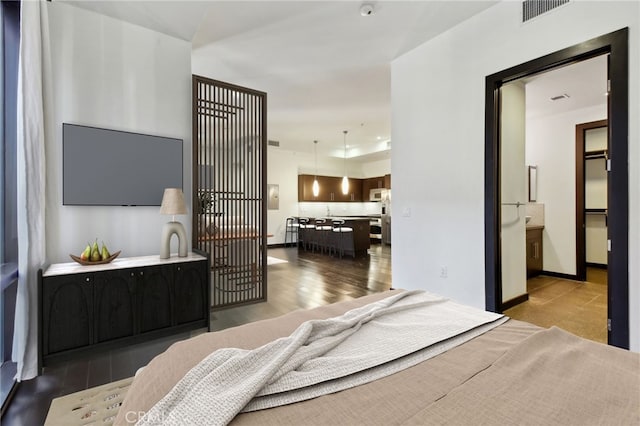 bedroom with freestanding refrigerator, wood finished floors, visible vents, and baseboards