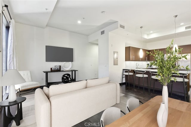 living room with dark wood-style floors, visible vents, and recessed lighting