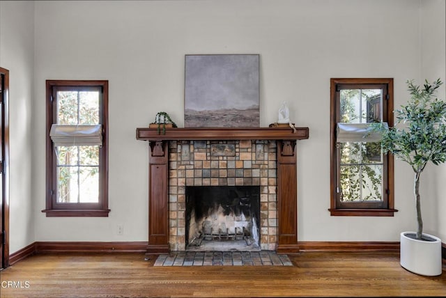 unfurnished living room with a fireplace with flush hearth, baseboards, and wood finished floors