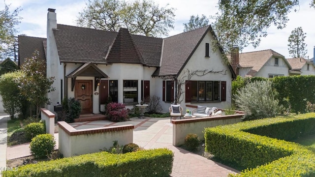 tudor home featuring a chimney and stucco siding