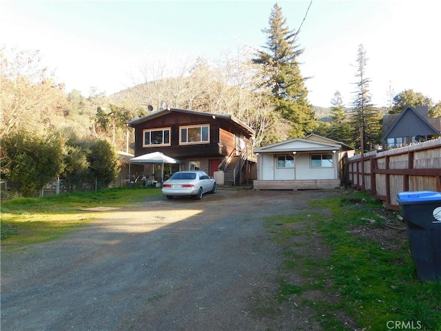 view of front of property featuring driveway, fence, and a mountain view